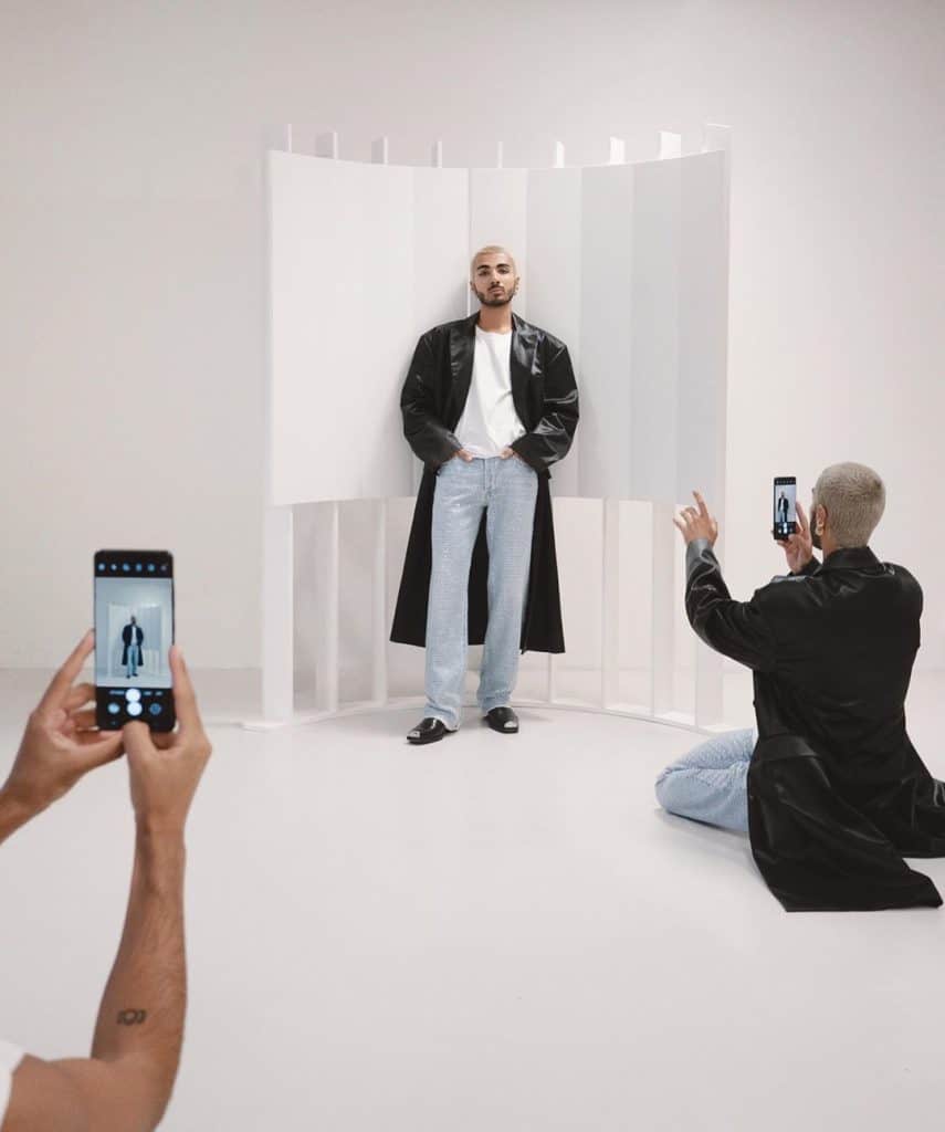 En man som poserar framför två som håller i en samsung telefon